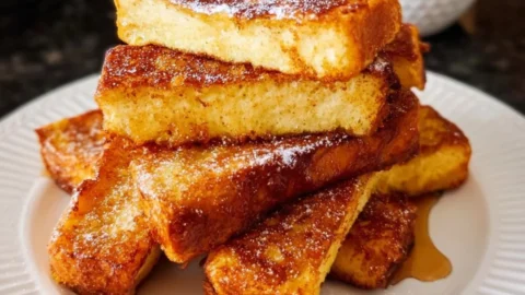 Crispy air fryer French toast sticks served with syrup and berries